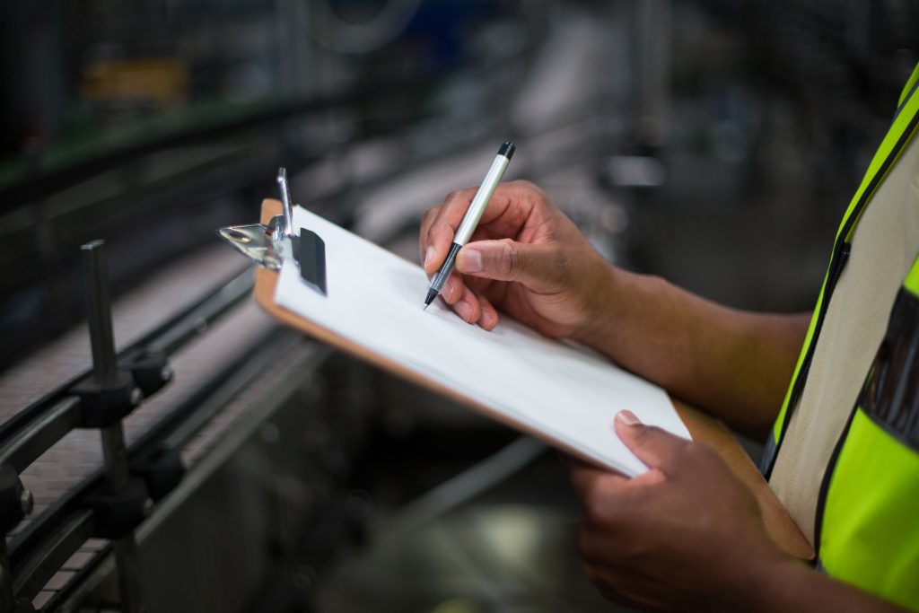 Factory worker writing on notepad in factory